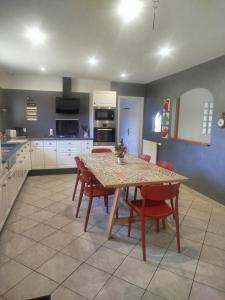 a kitchen with a table and red chairs in a room at Gîte La Pointe de Diamant in Brigné