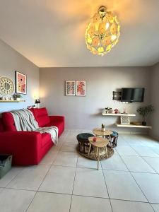 a living room with a red couch and a table at Escale Détente Genas proche Eurexpo in Genas