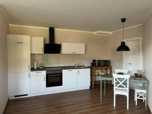 a kitchen with white cabinets and a table and chairs at Ferienwohnung Pommerbachquelle in Kaisersesch