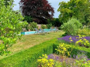 - un jardin avec une piscine, des chaises et des fleurs dans l'établissement Moorhen Cottage, à Hollingbourne