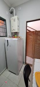 a kitchen with a refrigerator with a microwave on top of it at Quarto individual in Mogi das Cruzes