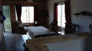 ein Wohnzimmer mit 2 Tischen und 2 Fenstern in der Unterkunft Rincón Peralta Córdoba in Valle Hermoso