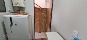 a small kitchen with a refrigerator and a door at Quarto individual in Mogi das Cruzes