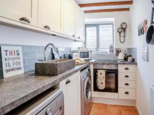 eine Küche mit weißen Schränken und einer Spüle in der Unterkunft The Old Cowsheds 5 - Llanilar - Uk49790 in Cribyn