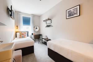 ロンドンにあるBorough High Street Roomsのベッド2台と机と窓のある寝室 +12枚の写真