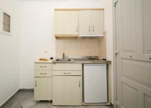 a kitchen with white cabinets and a sink and a dishwasher at Christiana Hotel in Ambelas