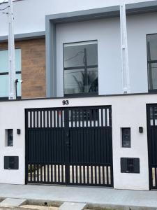 a black garage door on a white house at Loft de luxo em Peruíbe, 3 minutos da praia in Peruíbe