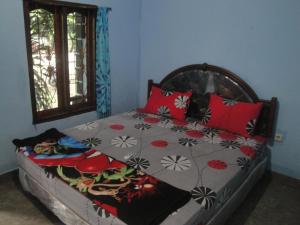 a bedroom with a bed with red pillows at Sawe Homestay in Kuta Lombok