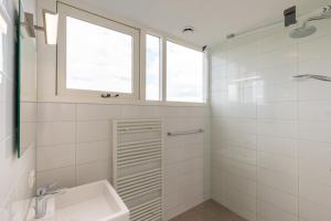 a white bathroom with a sink and a window at Welcome in - Zonnedorp Kavel 10 Renesse | Villa nabij het Strand & met Ruime Tuin in Renesse +42 photos