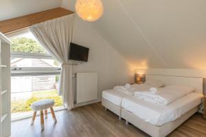 a bedroom with a bed and a tv and a window at Welcome in - Zonnedorp Kavel 10 Renesse | Villa nabij het Strand & met Ruime Tuin in Renesse