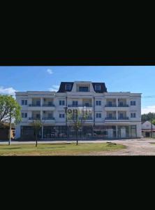 a large white building with trees in front of it at Apartman White Pearl in Palić