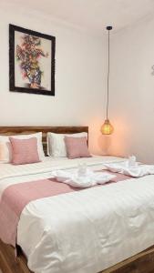 zwei Betten mit weißen Laken und rosa Kissen in der Unterkunft pondokasih in Uluwatu