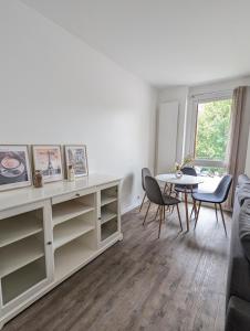 a white living room with a table and chairs at Évasion La Défense - Balcon & Wi-Fi, à 10 min de Paris in Courbevoie