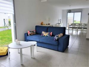 ein blaues Sofa im Wohnzimmer mit einem Tisch in der Unterkunft Maison familiale, proche des plages et des commerces in Piriac-sur-Mer