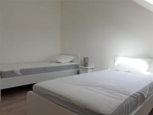 zwei Betten in einem Schlafzimmer mit weißen Wänden in der Unterkunft Maison familiale, proche des plages et des commerces in Piriac-sur-Mer