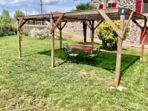 a picnic table under a wooden pergola in a yard at Gîte 2 personnes ! 