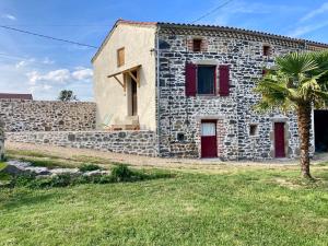 a stone house with red doors and a palm tree at Gîte 2 personnes ! 