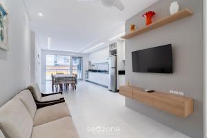 a living room with a couch and a tv on a wall at Apt w/ balcony and grill 220m from the Sea ALB0201 in Florianópolis