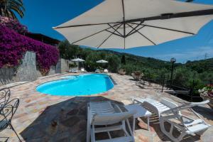 una piscina con sillas y sombrilla en Villaré, oasi di relax nel verde della Riviera con piscina privata, en Lavagna