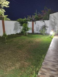 a yard at night with a white wall at Agréable in Hennchir Ksar Rhaleb