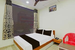 ein Schlafzimmer mit einem Bett und einem roten Stuhl in der Unterkunft hotel O kalyan in Rajkot