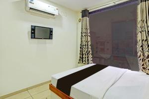 ein Schlafzimmer mit einem Bett, einem Fernseher und einem Fenster in der Unterkunft hotel O kalyan in Rajkot