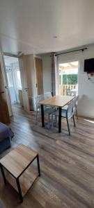 Una sala de estar con una mesa y sillas de madera. en Salsa confort, en Les Mathes