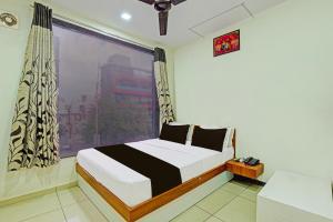 ein Schlafzimmer mit einem Bett und einem großen Fenster in der Unterkunft hotel O kalyan in Rajkot