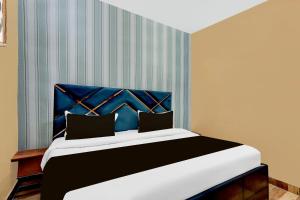 Un dormitorio con una cama grande con cabecero azul. en Hotel O Lotus Inn, en Faridabad