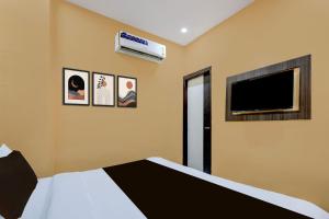 Un dormitorio con una cama y un televisor de pantalla plana. en Hotel O Lotus Inn, en Faridabad