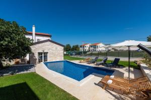 a swimming pool with chairs and an umbrella at Villa Nina with private pool and BBQ near Poreč in Bonaci