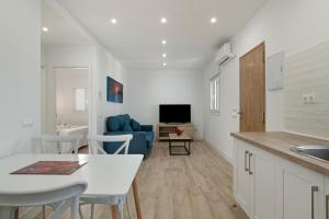 een keuken en een woonkamer met een tafel en een blauwe bank bij Casa Azul in Conil de la Frontera