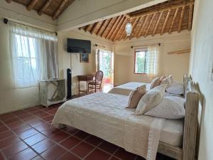 a bedroom with a bed with white sheets and a television at Ecohotel Santa Barbara in Circasia +58 photos