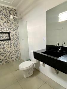 a white bathroom with a toilet and a sink at Parati - Hotel Pousada e Motel in Quatá