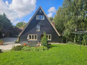 a black house with a gambrel roof on a yard at Plum Pudding Barn in Kent