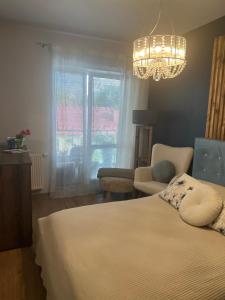a bedroom with a bed and a chandelier at Komfortowy apartament blisko Niegocina in Giżycko