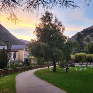 a park with a tree and some white chairs at Le Studio Louise Pratique & Central in Brides-les-Bains +6 photos