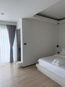 a white bedroom with a bed and a large window at Jellyfish Residence in Patong Beach +12 photos