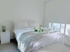 Una cama blanca con un osito de peluche encima. en Bright Airy Stay Apartment, en Sídney