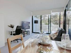 Una sala de estar con mesa y sillas y ventanas. en Bright Airy Stay Apartment, en Sídney