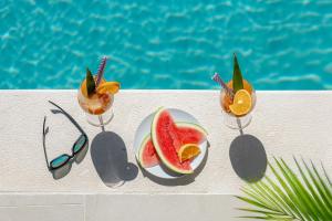 a plate of fruit and glasses next to a pool at Villa Lav Lux Elegant Residence with Private Heated Pool in Mlini