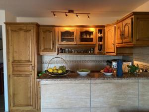a kitchen with wooden cabinets and a bowl of fruit at PALMERAIE 317-climatisation-plage et commerces à pieds in Sari Solenzara