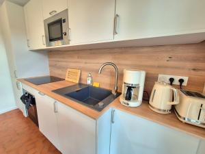 a kitchen counter with a sink and a microwave at Maison La Côtière proche plage avec parking in Camiers