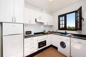 una cocina con gabinetes blancos y una lavadora y secadora en Villa Dorada by Villa Plus, en Playa Blanca