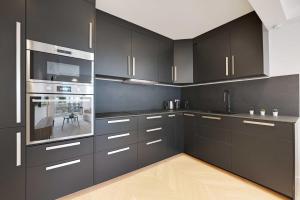 a kitchen with black cabinets and stainless steel appliances at Charming Apt with AC & balcony in Suresnes