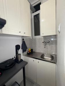 a kitchen with white cabinets and a sink at Le Bel Appartement D'Antigoni in Alexandroupoli +25 photos