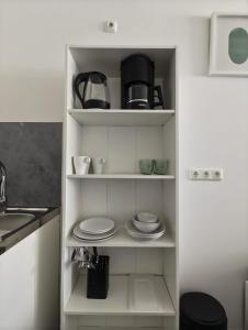 a kitchen pantry with plates and a coffee maker at Serviced Apartments Augsburg Lechhausen in Augsburg