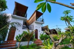 ein Haus mit zwei Balkonen und Palmen in der Unterkunft Rostin Mesari Villa in Nusa Penida