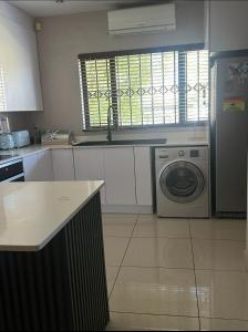 una cocina con nevera y lavadora en Riverside Gardens 2 bedroom Home, en Nelspruit