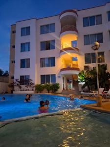 a group of people swimming in a pool in front of a building at Departamento en la Playa in Tonsupa